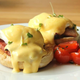 eggs benedict on a plate with grape tomatoes